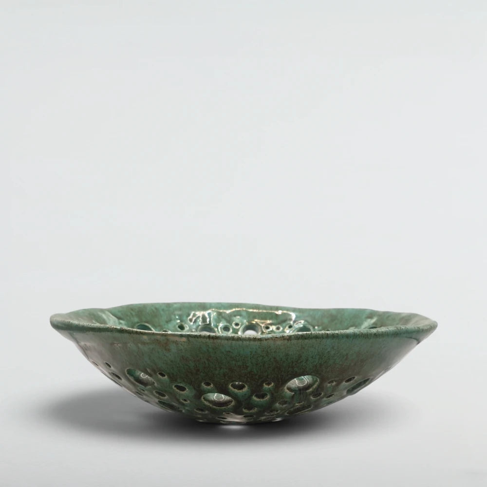 Side view of the Atoll pierced ceramic bowl showing the lace-like wall and speckled green glaze