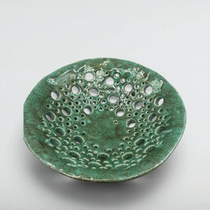Pierced stoneware fruit bowl from above, showing verdigris glaze breaking around dozens of hand-cut holes