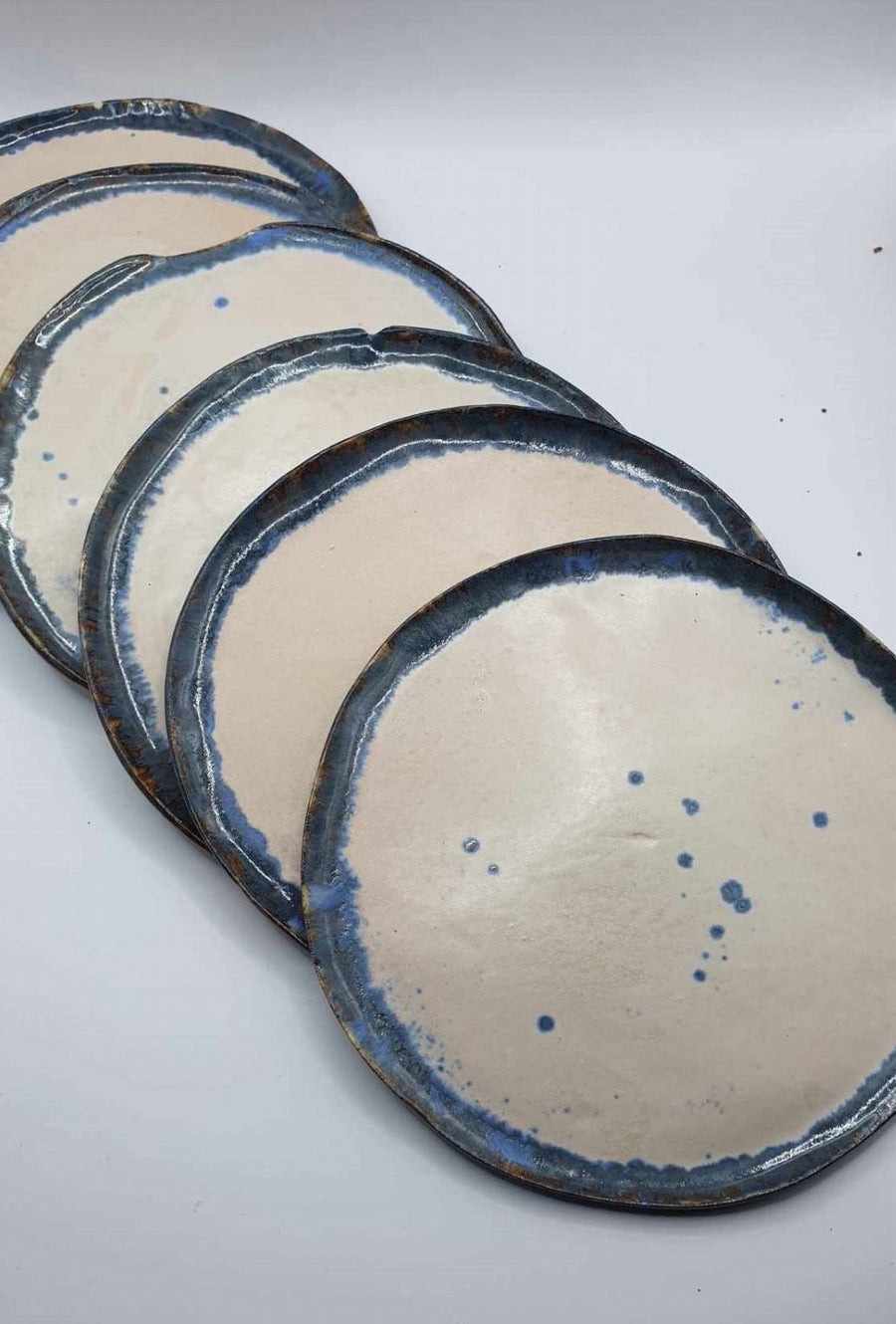 Set of five handmade stoneware dessert plates with indigo and bronze glaze variations, fanned out