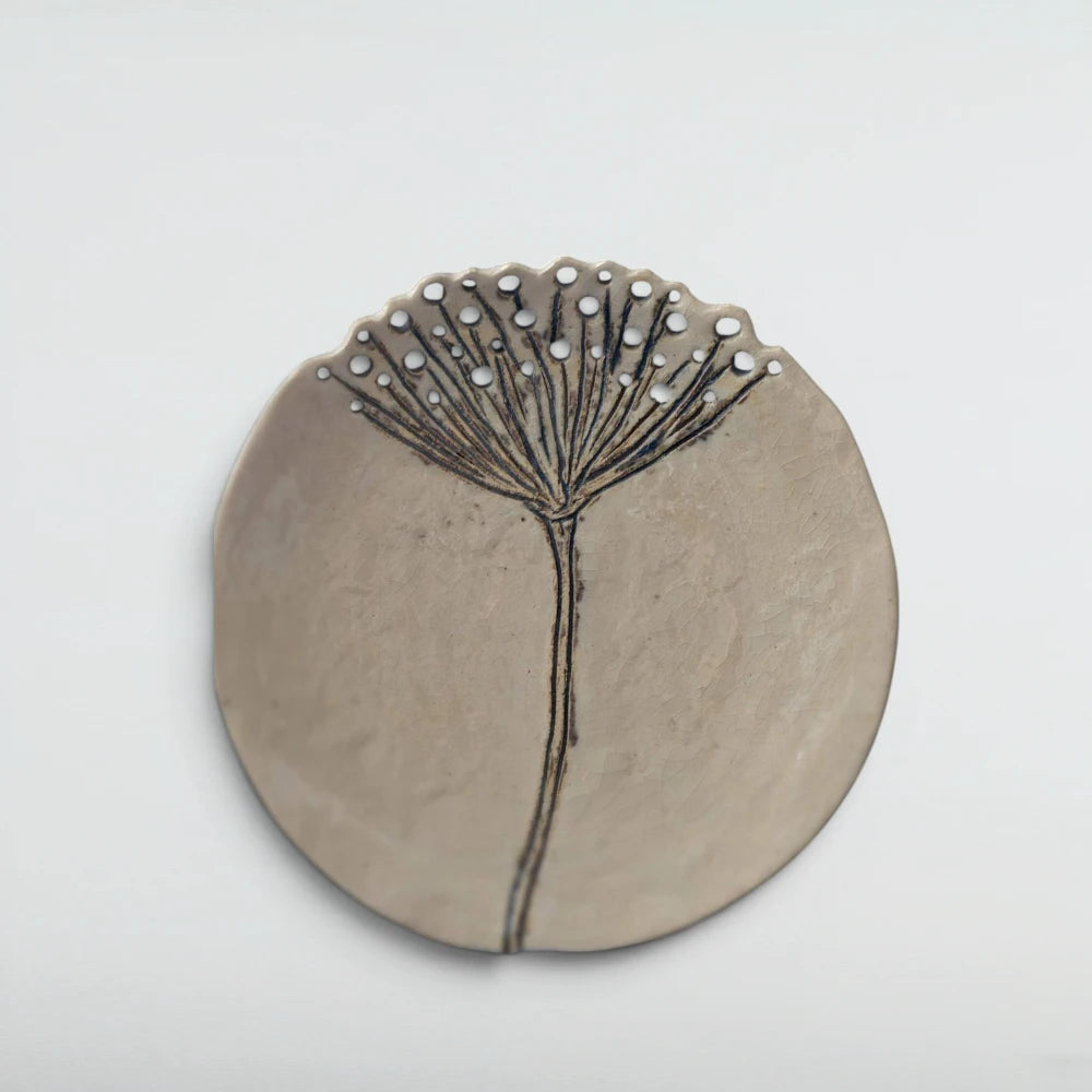 Cream crackle-glazed ceramic wall plate carved with a single wild yarrow stem, its flower head bursting into pierced holes